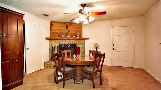 dining area featuring visible vents, crown molding, a fireplace, light colored carpet, and ceiling fan
