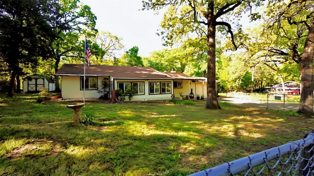 rear view of property featuring an outdoor structure, fence, a yard, and a storage unit