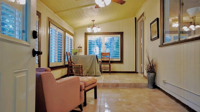 interior space featuring light tile patterned floors, baseboards, a healthy amount of sunlight, and ceiling fan with notable chandelier