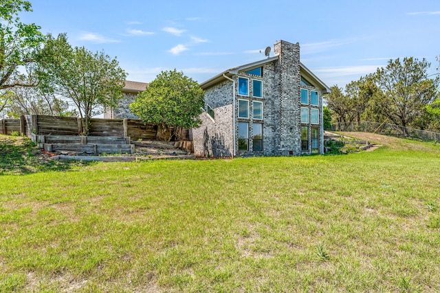 rear view of house featuring fence, a lawn, and a chimney