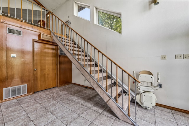 stairway with baseboards, tile patterned floors, a towering ceiling, and visible vents