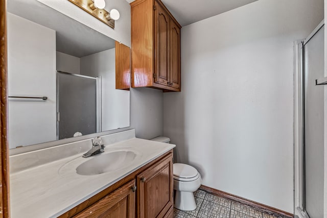 bathroom with a shower stall, tile patterned floors, toilet, vanity, and baseboards
