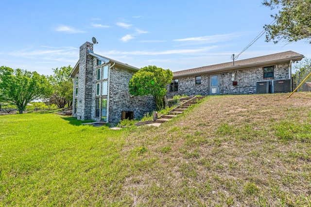 back of property with a chimney, stairway, and a lawn