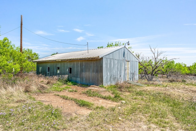 exterior space with fence, an outbuilding, an outdoor structure, and metal roof