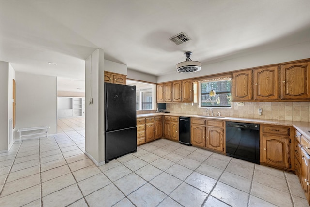 kitchen featuring light countertops, tasteful backsplash, a sink, and black appliances