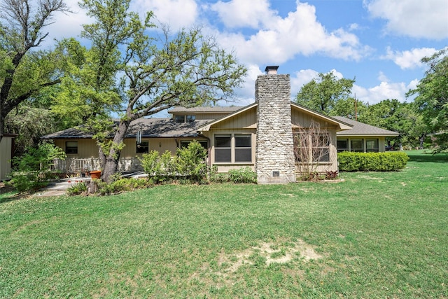 rear view of property featuring a chimney and a yard