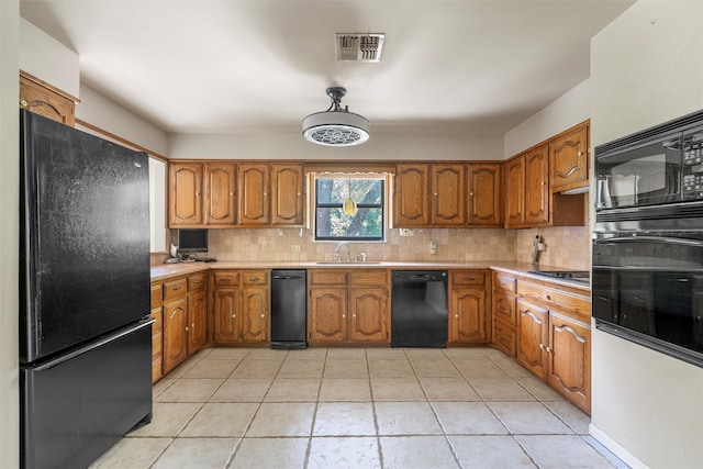 kitchen featuring a sink, black appliances, brown cabinets, backsplash, and visible vents
