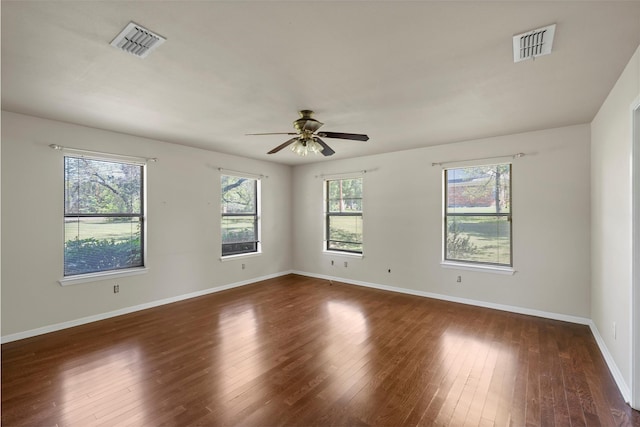spare room with baseboards, visible vents, ceiling fan, and dark wood finished floors