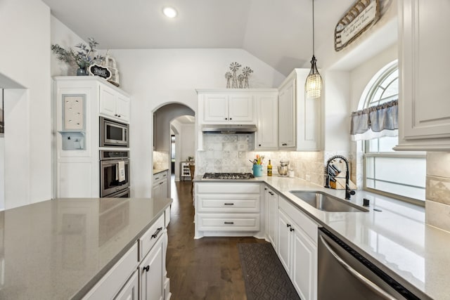 kitchen featuring stainless steel appliances, arched walkways, a sink, white cabinetry, and under cabinet range hood
