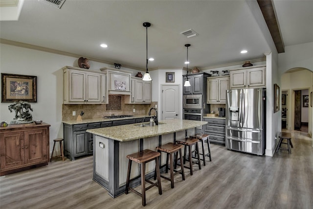 1601 Harbor Lakes Dr, Granbury, TX 76048 - kitchen featuring stainless steel appliances, arched walkways, a sink, a breakfast bar area, and decorative backsplash