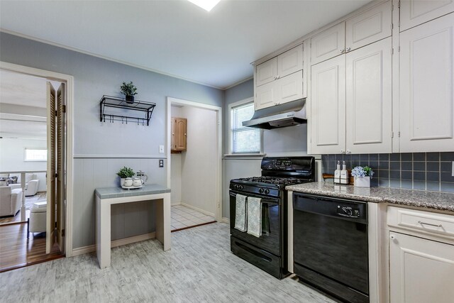 kitchen with under cabinet range hood, light wood-style floors, crown molding, decorative backsplash, and black appliances