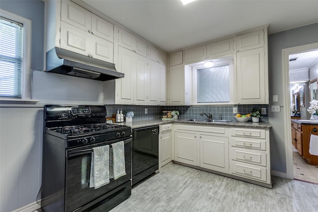 kitchen with under cabinet range hood, a sink, light wood-type flooring, black appliances, and tasteful backsplash