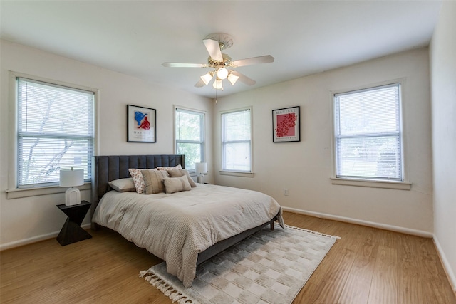 bedroom featuring light wood-type flooring, a ceiling fan, baseboards, and multiple windows