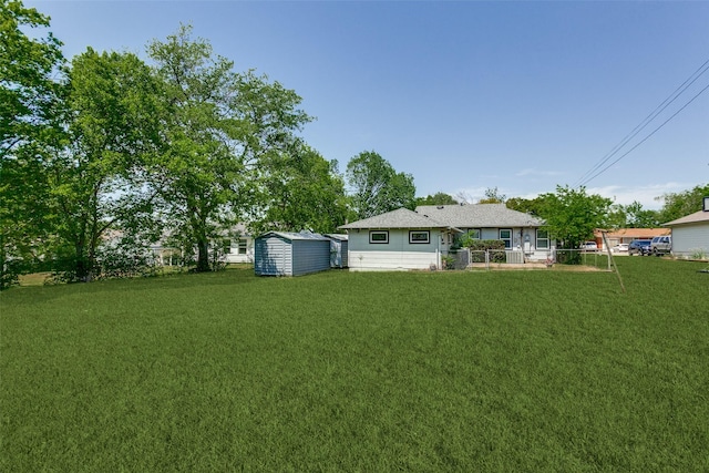 view of yard with fence, a storage unit, and an outdoor structure