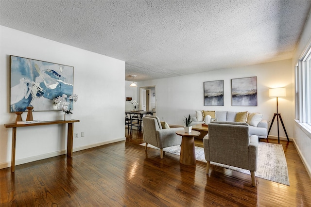 living area with wood-type flooring, a textured ceiling, and baseboards