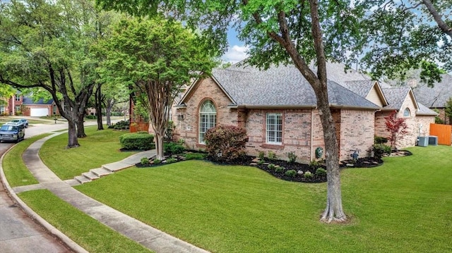 english style home with brick siding, a shingled roof, and a front lawn
