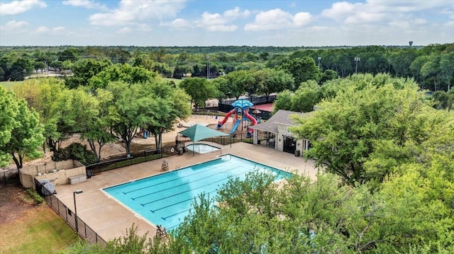 community pool featuring a forest view and fence