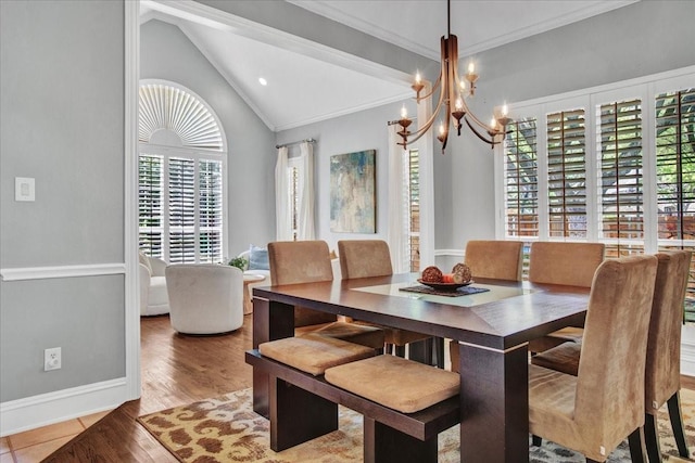 dining room with vaulted ceiling, wood finished floors, ornamental molding, baseboards, and a chandelier