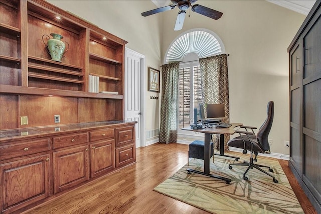 office featuring baseboards, a ceiling fan, a towering ceiling, and light wood finished floors