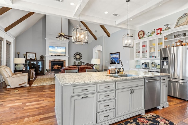 kitchen with beam ceiling, a sink, light wood-type flooring, visible vents, and appliances with stainless steel finishes