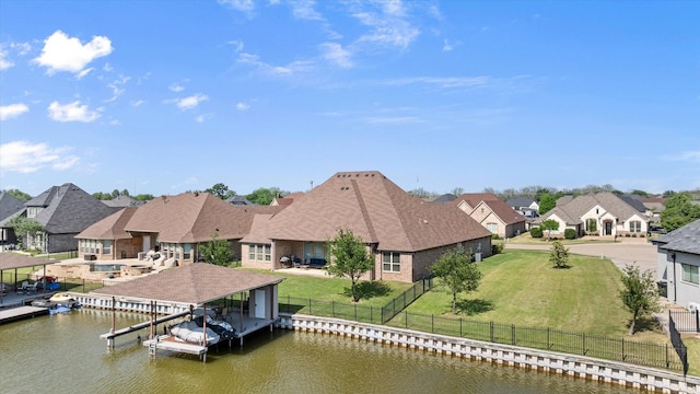 view of dock featuring a residential view, a fenced backyard, a water view, boat lift, and a yard