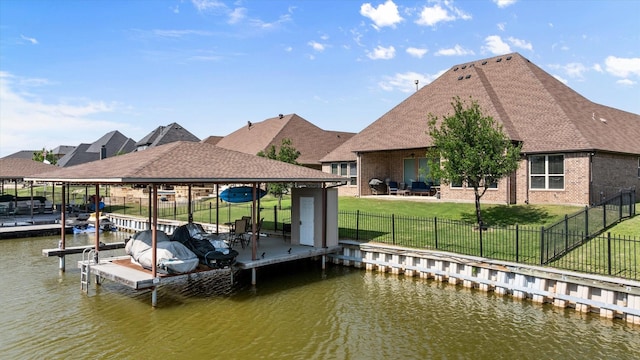 dock area featuring a yard, a fenced backyard, and a water view