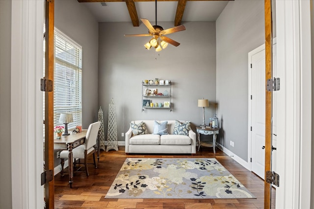 sitting room with ceiling fan, baseboards, wood finished floors, and beamed ceiling