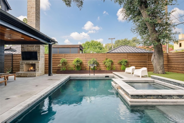 view of swimming pool featuring an outdoor stone fireplace, a patio area, a fenced in pool, a fenced backyard, and an in ground hot tub