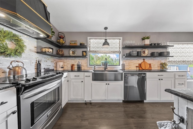 kitchen with open shelves, dark countertops, a sink, appliances with stainless steel finishes, and custom range hood
