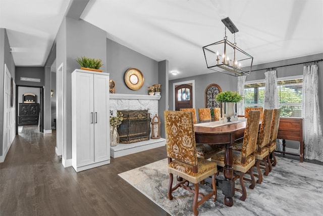 dining space with a chandelier, wood finished floors, baseboards, and a stone fireplace