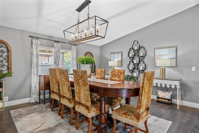 dining room with a chandelier, wood finished floors, lofted ceiling, and baseboards