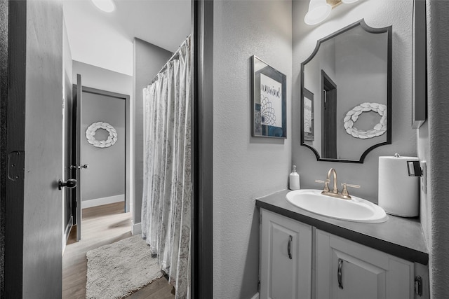 bathroom featuring wood finished floors, vanity, and a textured wall