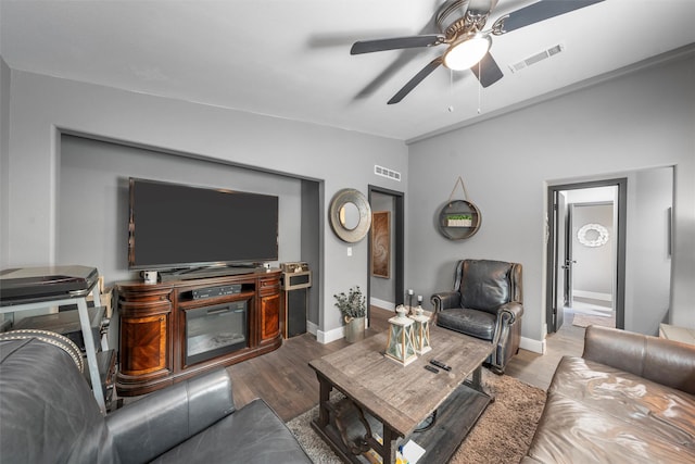 living room with wood finished floors, visible vents, baseboards, and ceiling fan