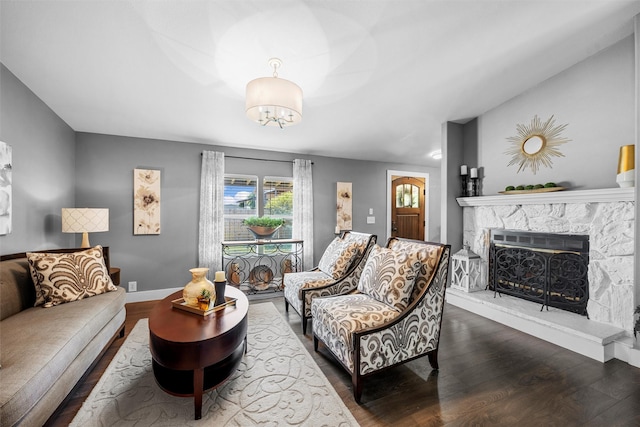 living area featuring baseboards, dark wood-style flooring, a chandelier, and a fireplace