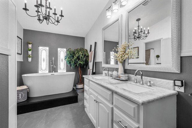 full bath featuring a chandelier, a freestanding tub, marble finish floor, and a sink