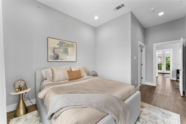 bedroom with baseboards, french doors, wood finished floors, and visible vents