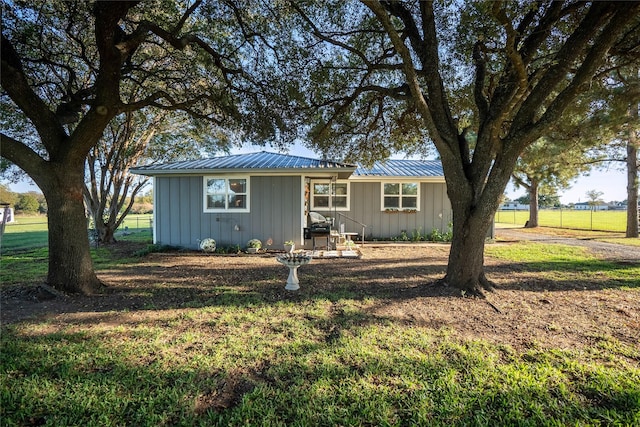 single story home featuring board and batten siding, a front yard, and metal roof