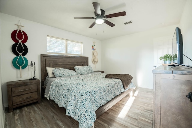 bedroom with ceiling fan, baseboards, wood finished floors, and visible vents