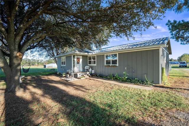 ranch-style home featuring fence, board and batten siding, and metal roof