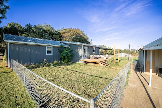back of house featuring a lawn, a deck, an outdoor hangout area, a fenced backyard, and metal roof