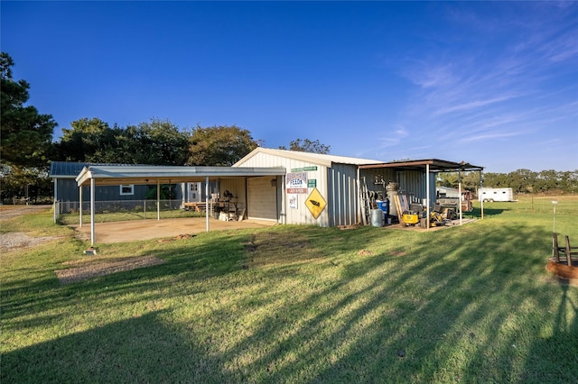 back of house with fence, board and batten siding, an outdoor structure, a detached garage, and a lawn