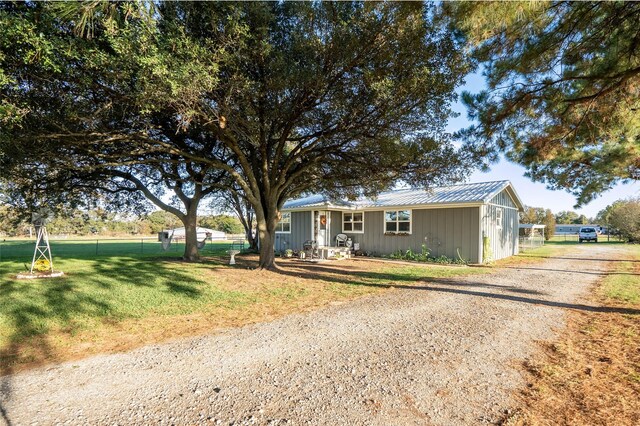 ranch-style house featuring driveway, board and batten siding, fence, a front yard, and metal roof