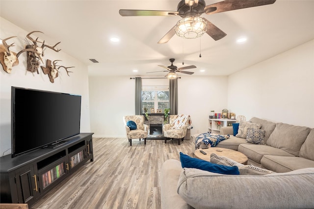 living room featuring a ceiling fan, wood finished floors, baseboards, visible vents, and recessed lighting