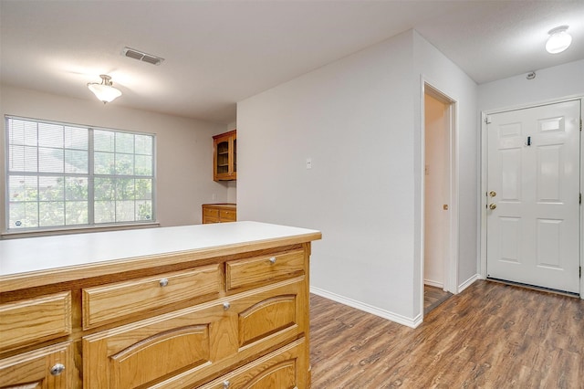 kitchen with baseboards, wood finished floors, visible vents, and light countertops