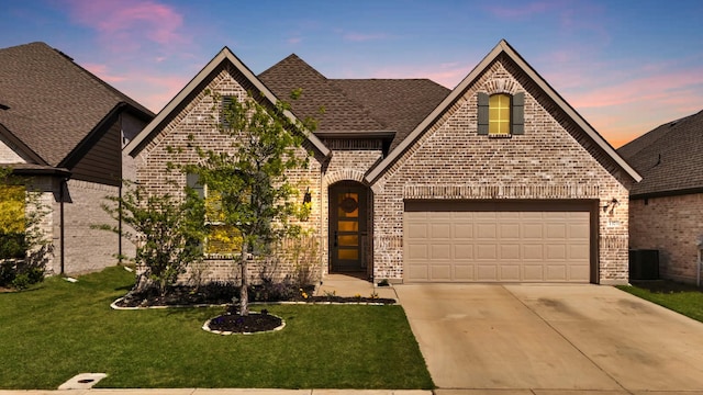 view of front of property with driveway, brick siding, a yard, and a garage