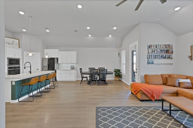 living room featuring vaulted ceiling, a ceiling fan, light wood-style floors, visible vents, and recessed lighting