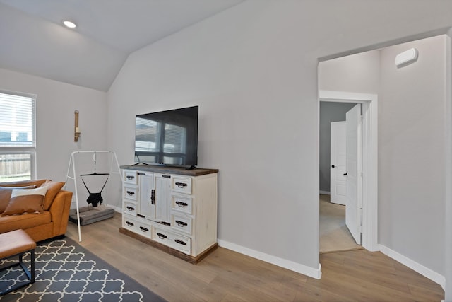sitting room with light wood-type flooring, vaulted ceiling, and baseboards