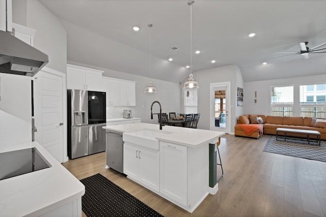 kitchen featuring stainless steel appliances, light wood-style flooring, a sink, lofted ceiling, and light countertops