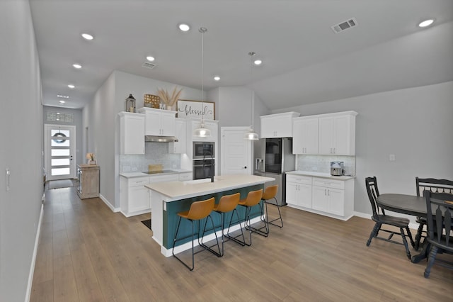 kitchen featuring visible vents, white cabinetry, light countertops, under cabinet range hood, and black appliances