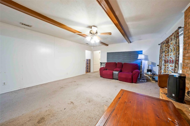 carpeted living area with visible vents, ceiling fan, and beam ceiling